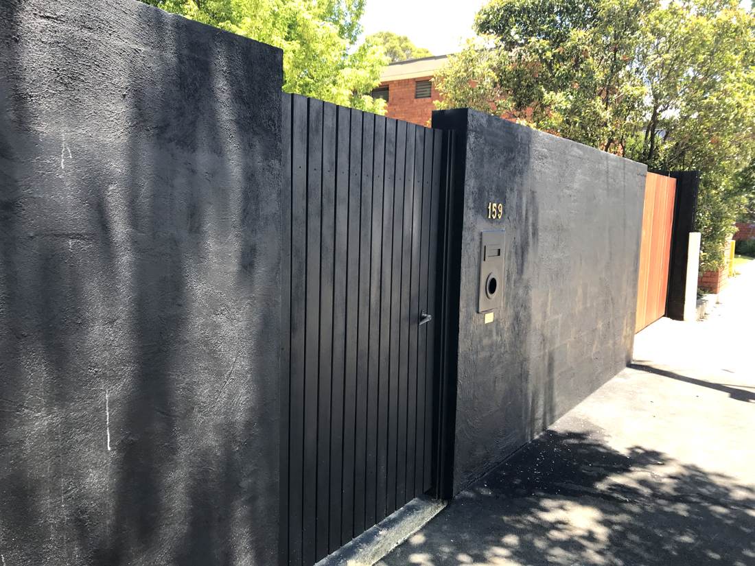 Black rendered boundary wall with brass 159 numerals, letterbox and timber batten gate