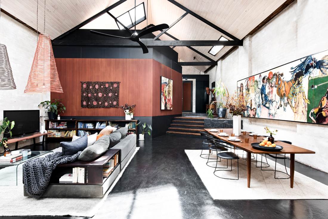 Living and dining space with sapele timber-clad central volume, Indigenous artwork and woven cone pendants