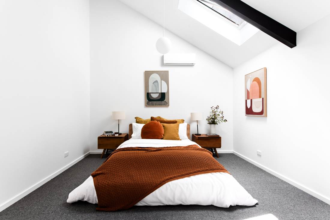 Attic bedroom with skylight, black steel beam and warm rust and ochre textiles