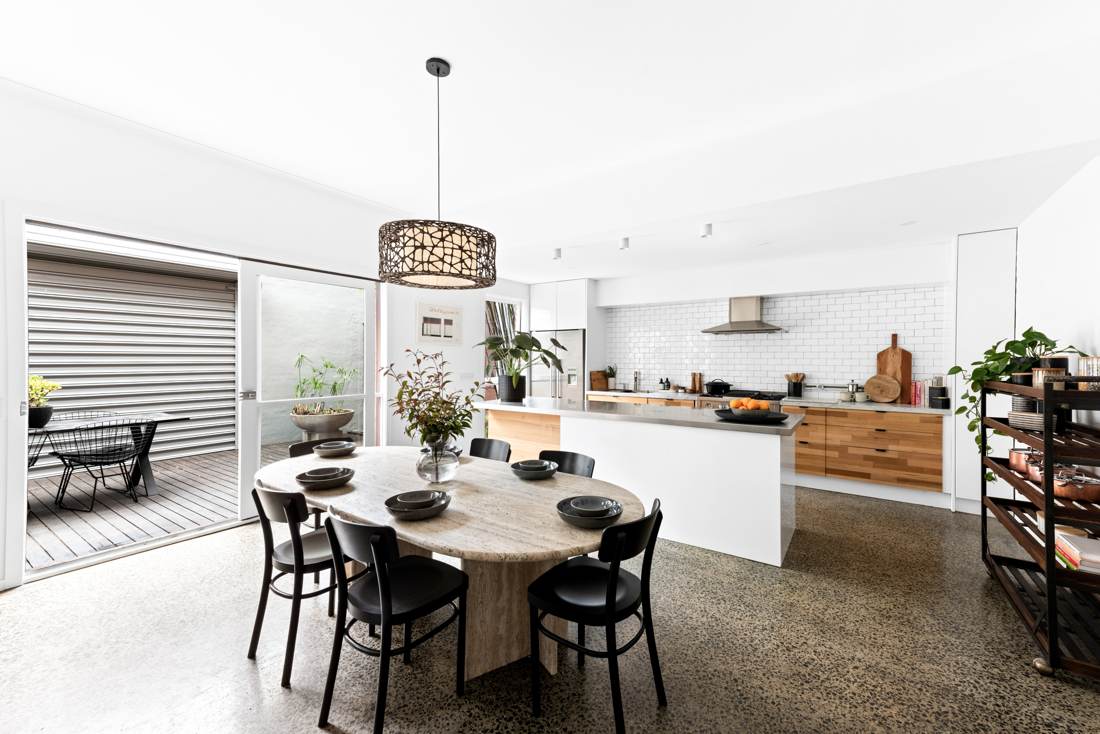Open kitchen and dining with stainless island, timber drawers, subway tiles and travertine table