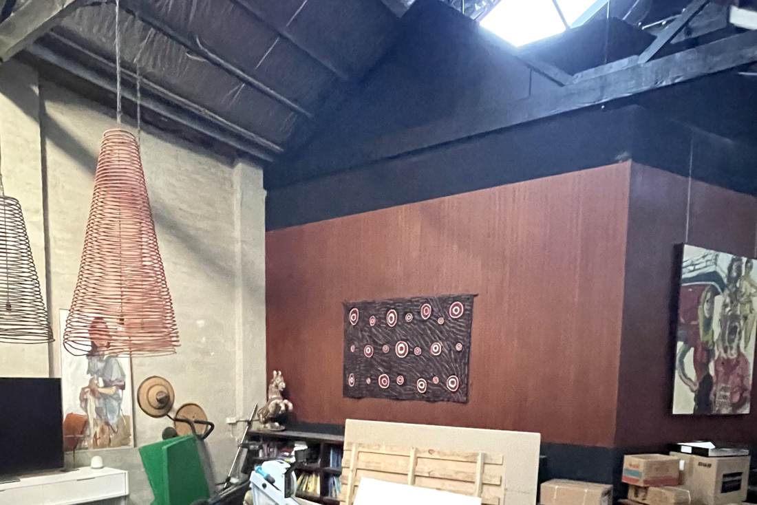 The warehouse living space before renovation — dark floors, clutter and exercise equipment