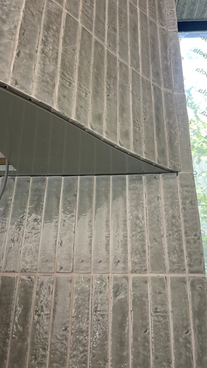 Close detail of the curved rangehood — pale fluted tile following the curve