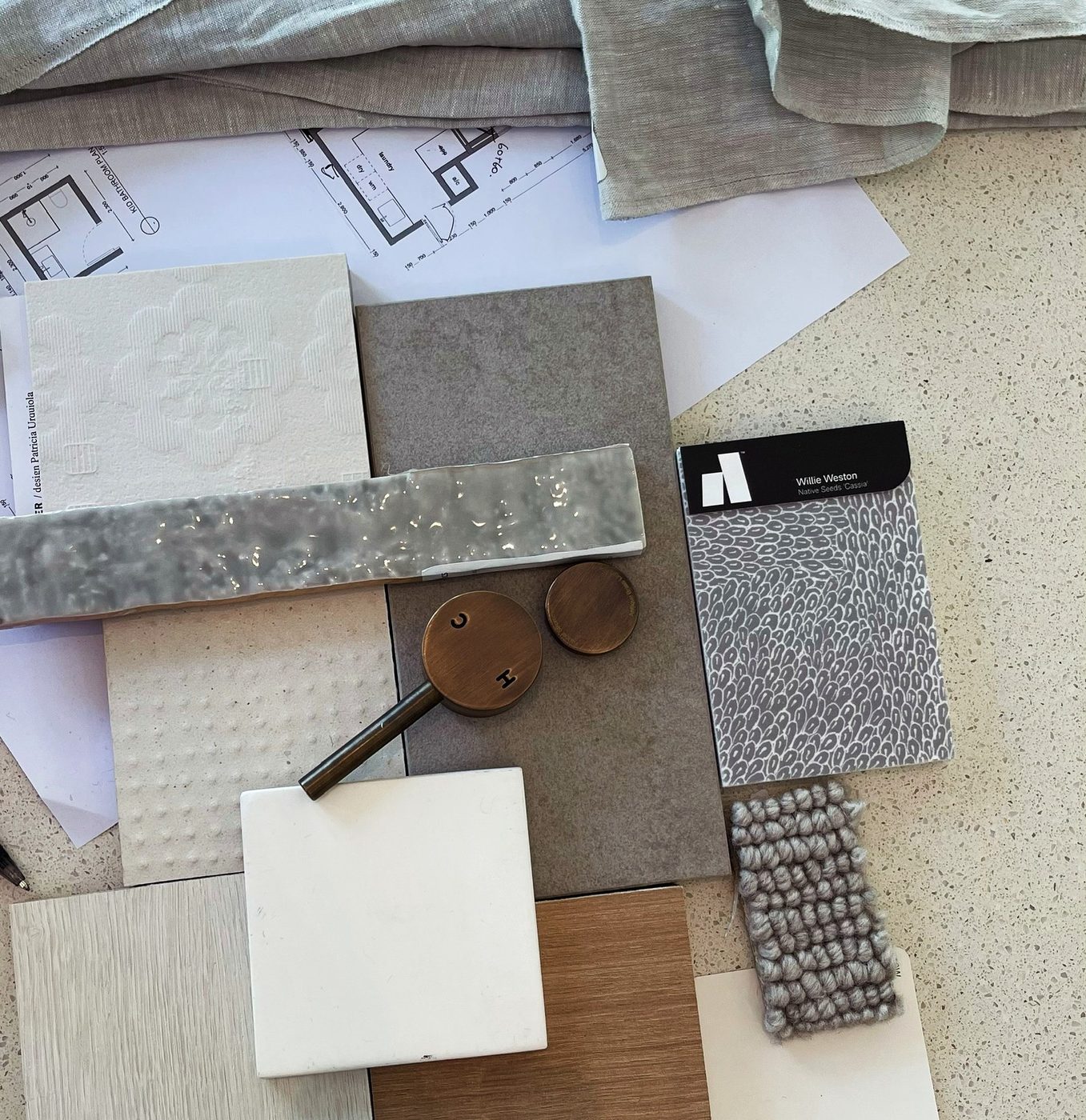 The Staniland material palette — sage stone, natural linens, wool carpet, aged brass and pale fluted tile, laid out together