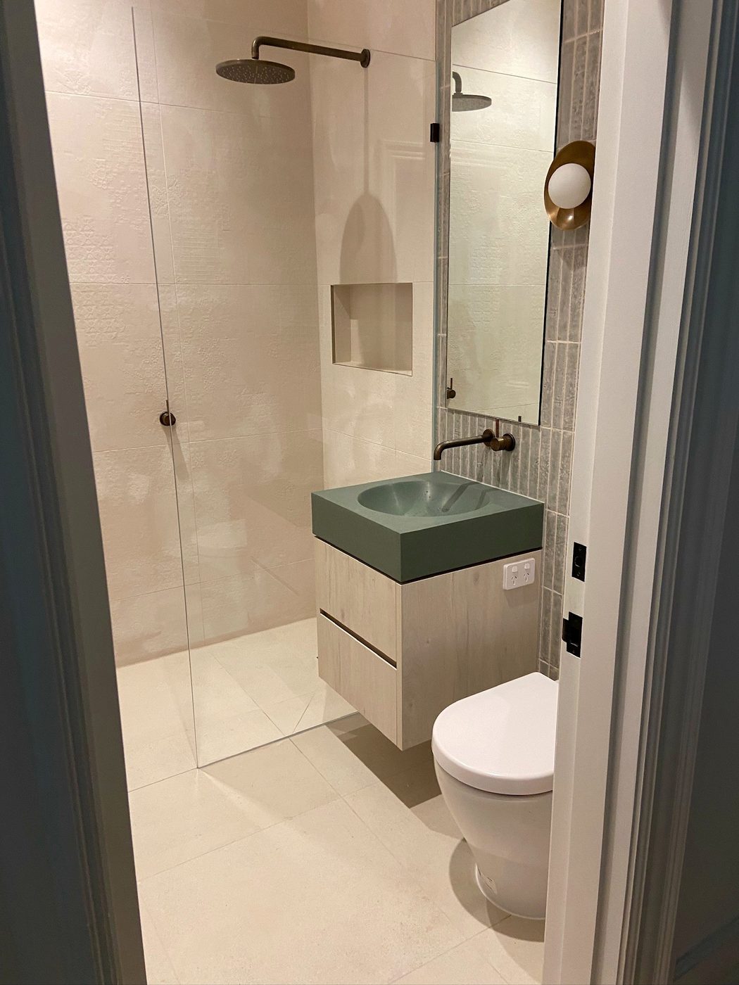 The powder room — a green Apaiser stone basin on timber joinery