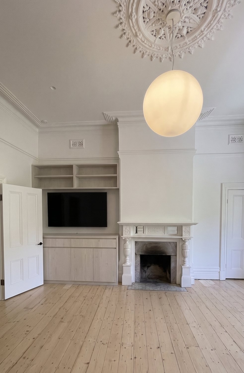The formal lounge — original ceiling rose and mantel restored, new grey-washed timber joinery and pale floors