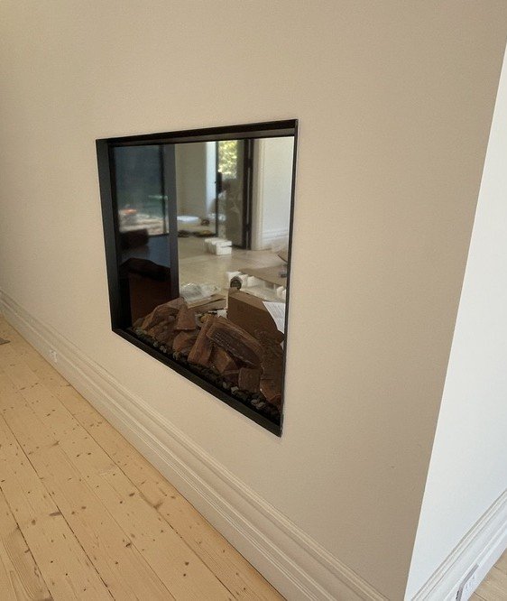 The new three-way fireplace — a black-framed firebox set into the wall between hall and living rooms