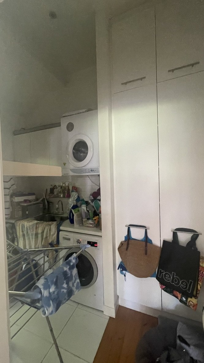 The laundry before the work — a cramped white room with stacked machines