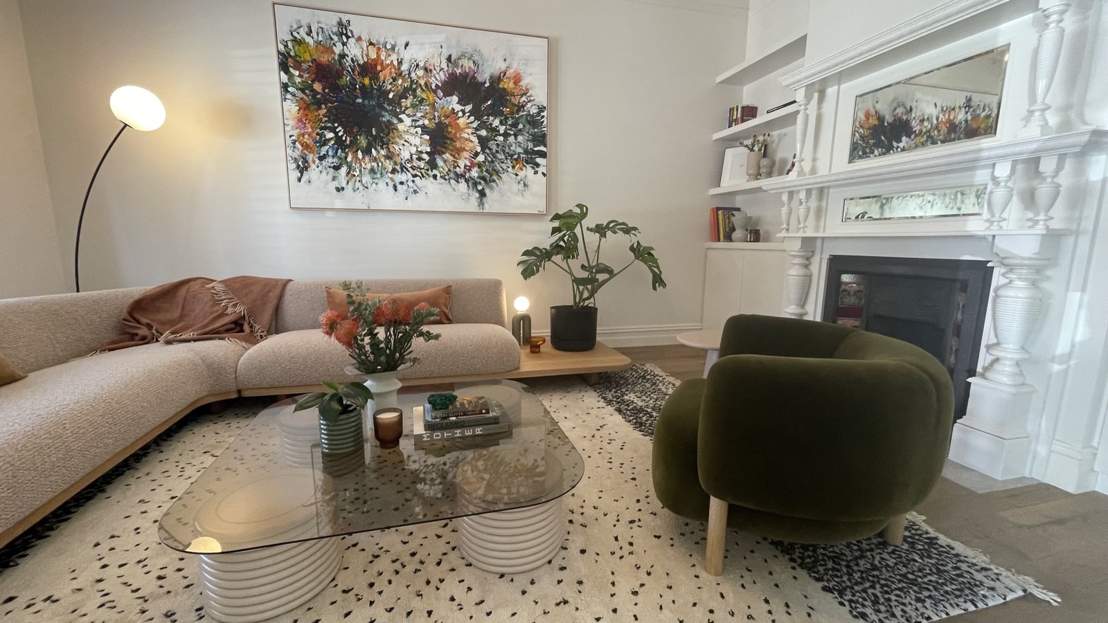 The formal lounge — the original overmantel restored and painted white, green velvet chair beside it, commissioned Michael Bond artwork