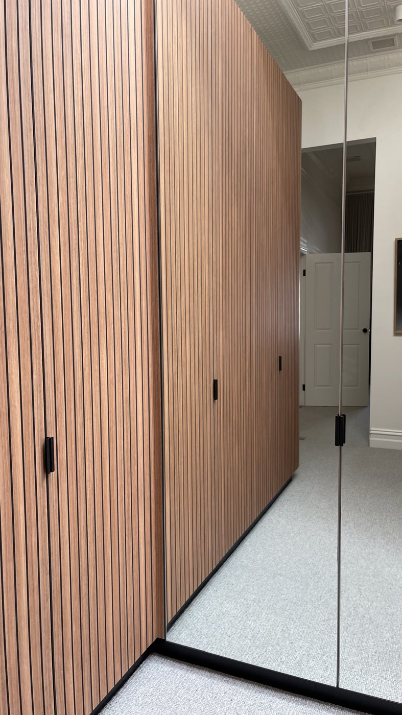 The walk-in robe — battened timber joinery and mirrored robes beneath the pressed-metal ceiling