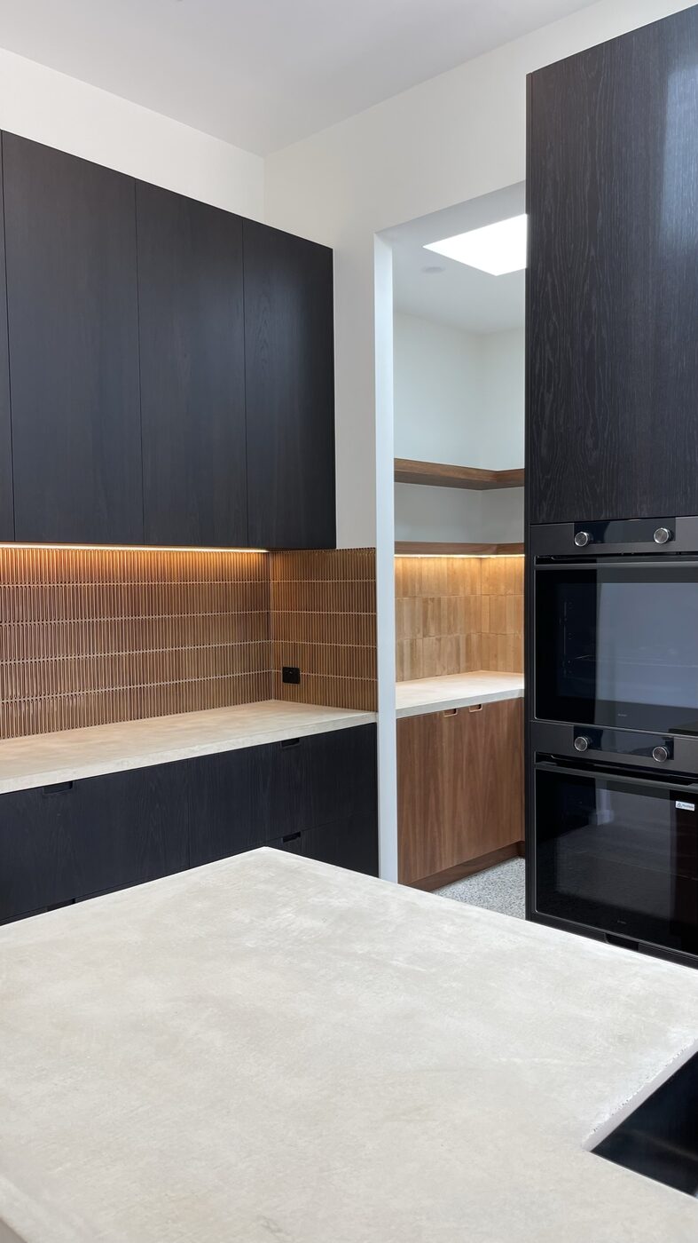 From the island across to the butler's pantry — one palette carried through both rooms