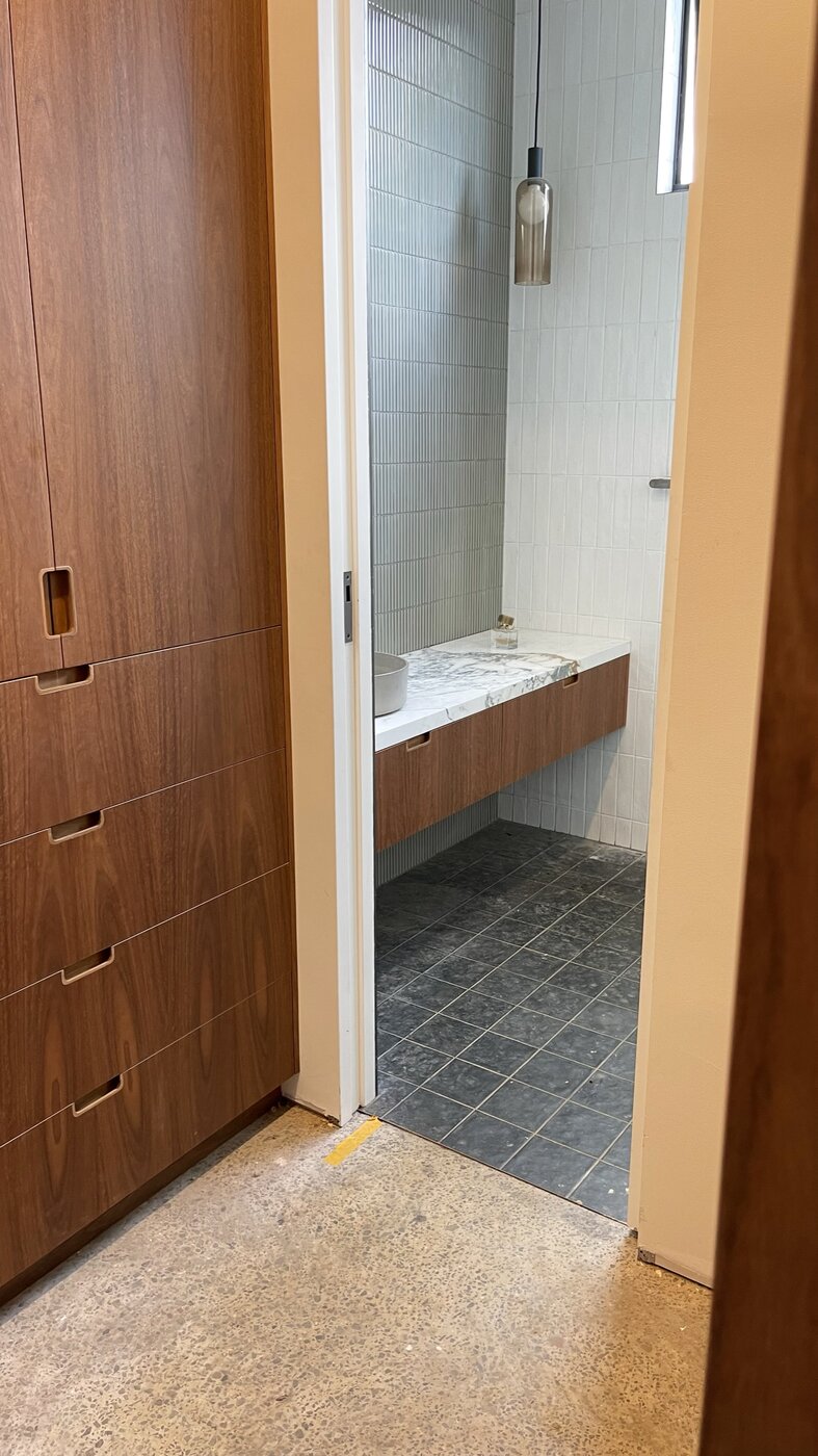 Through the walk-in robe to the ensuite — spotted gum robes giving onto the floating marble vanity and slate floor