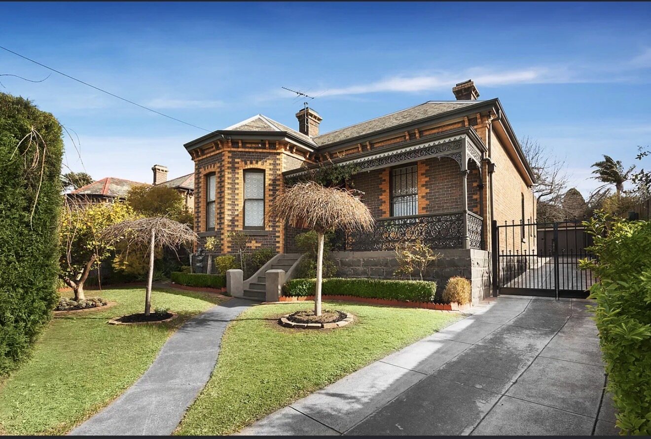 The retained heritage facade — polychrome brick Victorian with cast-iron lacework and a bullnose verandah, left untouched